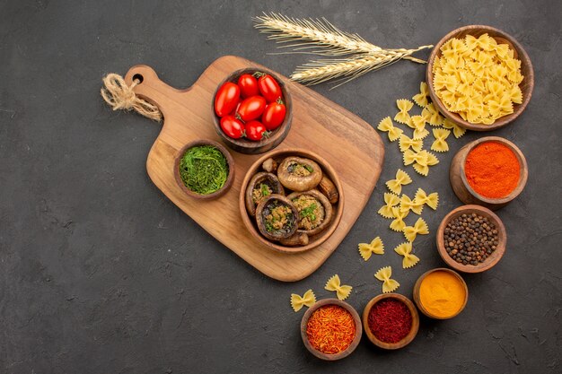 Vue de dessus champignons cuits avec assaisonnements sur table noire champignon alimentaire mûr