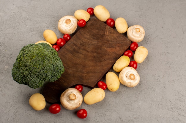 Vue de dessus des champignons de pommes de terre au brocoli avec des tomates cerises rouges sur le bureau gris