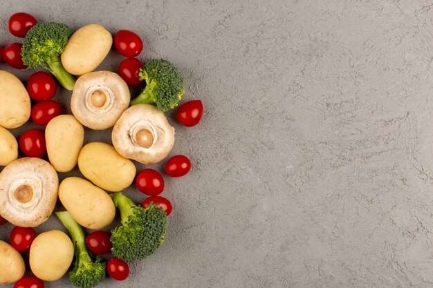 Vue de dessus des champignons avec des tomates cerises rouges et du brocoli bien mûrs sur le sol clair