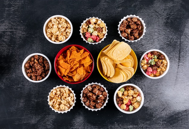 Vue de dessus des chips et du pop-corn dans des bols sur horizontal noir