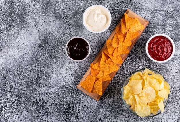 Vue de dessus chips et saucisses dans des bols et copie espace à gauche sur pierre blanche