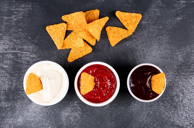 Vue de dessus des chips avec des saucisses dans des bols sur pierre noire