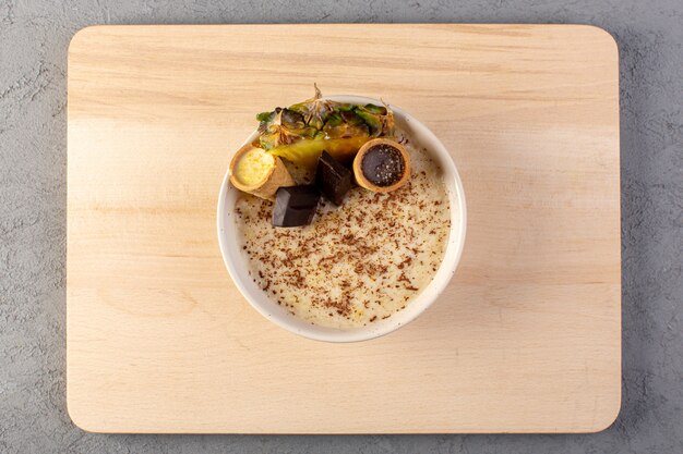 Une vue de dessus choco dessert marron avec une tranche d'ananas choco bars crème glacée à l'intérieur de la plaque blanche sur la crème et le gris