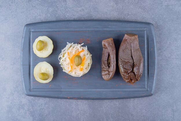 Vue de dessus de la choucroute avec des cornichons d'aubergines remplis sur une planche de bois grise.