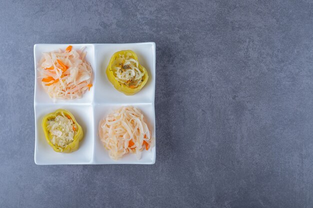 Vue de dessus de la choucroute et des poivrons verts fourrés sur une plaque blanche.