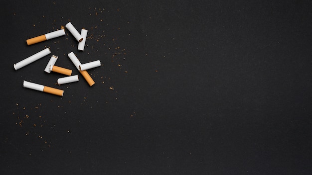 Photo gratuite vue de dessus d'une cigarette cassée avec du tabac sur fond noir