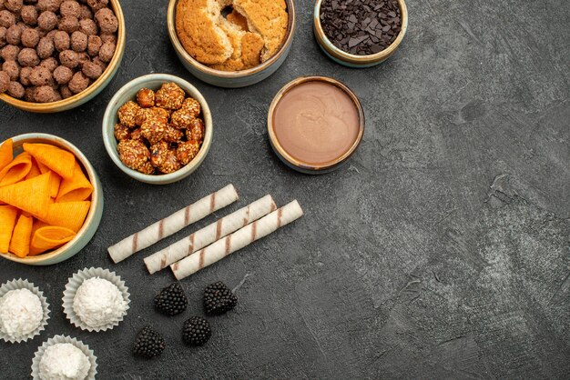 Vue de dessus des cips orange avec des noix sucrées et des flocons de chocolat sur un sol gris foncé collation collation petit-déjeuner noix