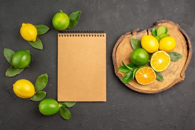 Vue de dessus citrons aigres frais sur la table gris foncé fruits agrumes citron vert