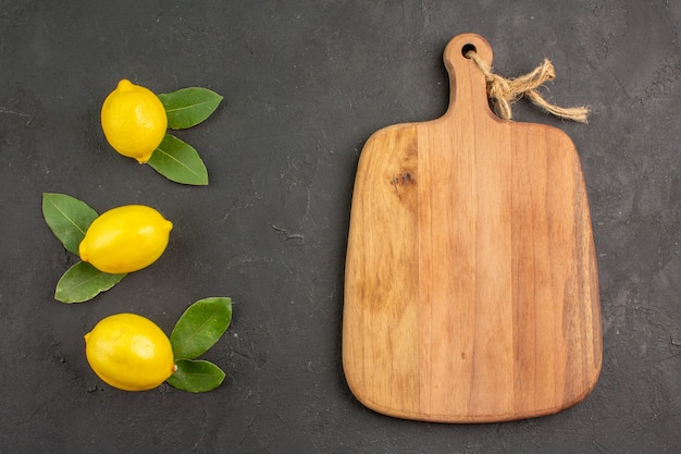 Vue de dessus citrons aigres frais sur la table sombre citron citron vert fruits jaunes