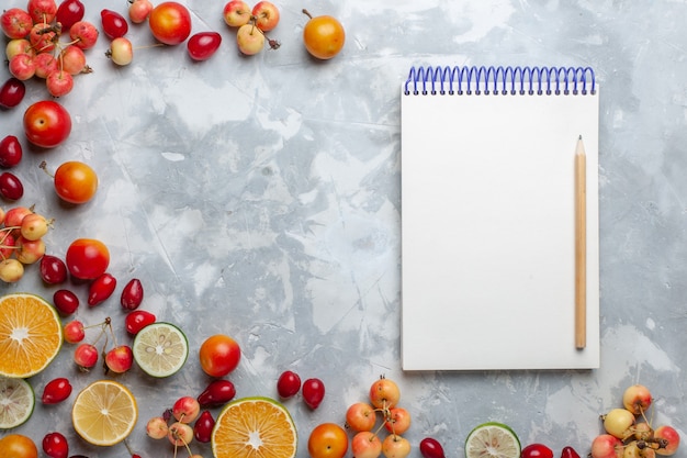 Vue de dessus citrons et cerises fruits frais avec bloc-notes sur le bureau léger fruits frais mûrs mûrs