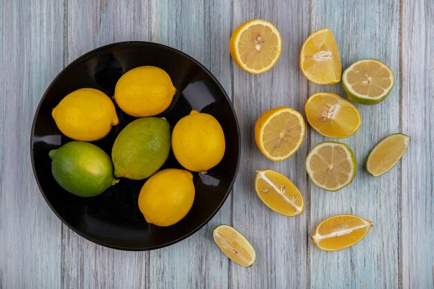 Vue de dessus citrons à la chaux sur une plaque noire avec des coins sur un fond gris