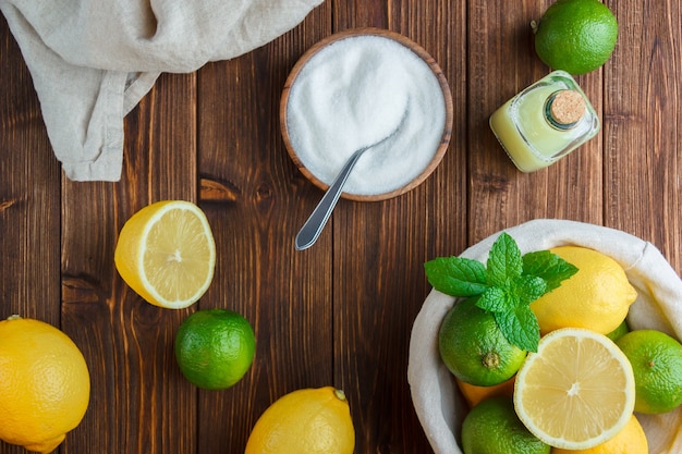 Vue de dessus citrons dans le panier avec un chiffon blanc, bol de sel, moitié de citron sur une surface en bois. verticale