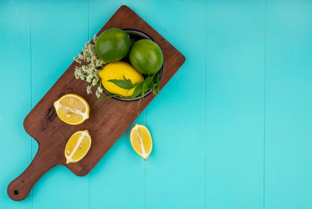 Vue de dessus de citrons frais et colorés sur planche de cuisine en bois sur bleu