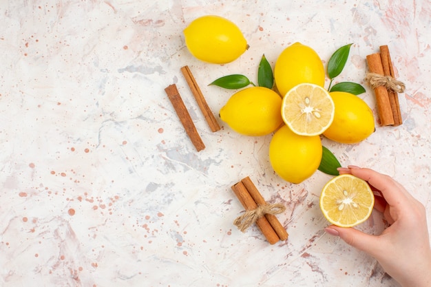 Vue de dessus des citrons frais couper le citron en bâtons de cannelle main féminine sur l'espace libre de surface isolée lumineuse