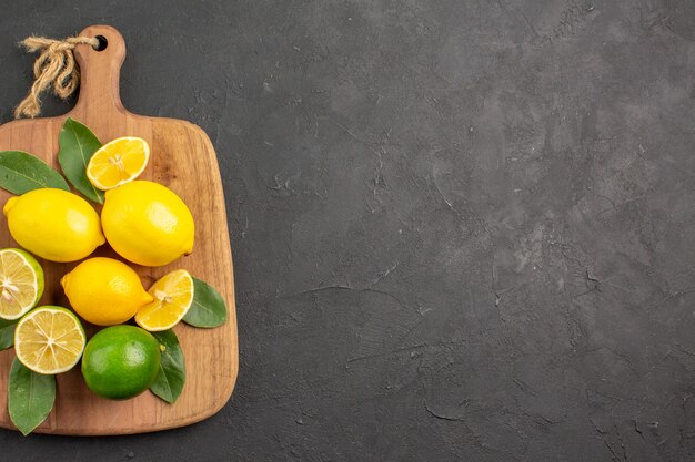 Vue de dessus citrons frais fruits aigres sur table gris foncé agrumes citron vert