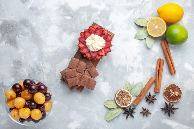 Vue de dessus citrons frais juteux et aigres avec des cerises à la cannelle sur un bureau léger agrumes de fruits exotiques tropicaux