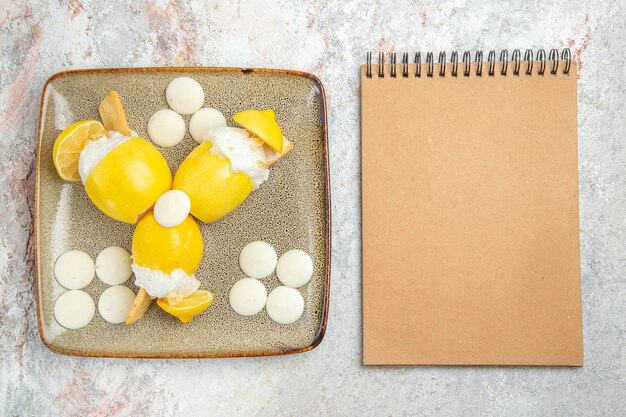 Vue de dessus citrons glacés avec des bonbons blancs sur le tableau blanc