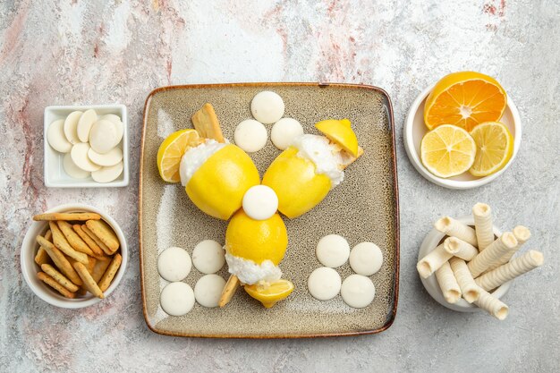 Vue de dessus citrons glacés avec des bonbons et des craquelins sur tableau blanc