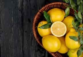 Photo gratuite vue de dessus de citrons mûrs frais dans un panier en osier sur fond noir avec espace copie