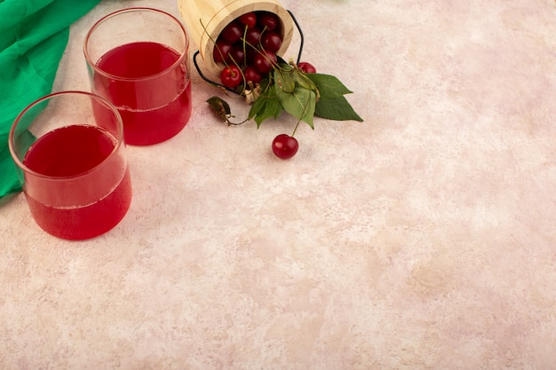 Une vue de dessus cocktail cerise rouge à l'intérieur de petits verres de refroidissement frais avec des cerises fraîches sur rose