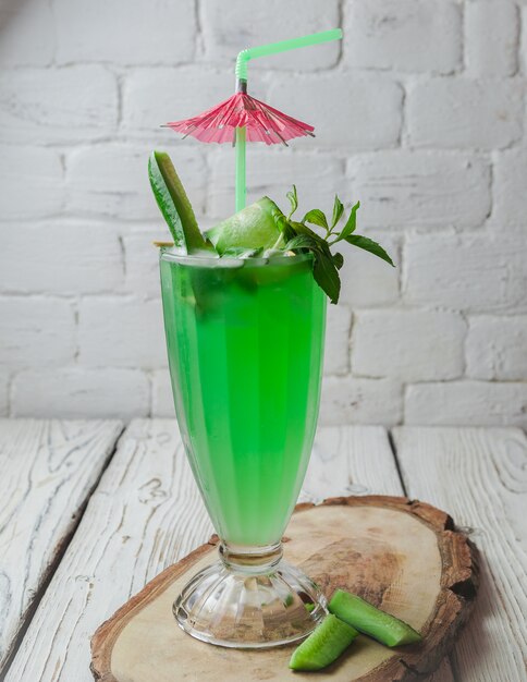 Vue de dessus cocktail de concombre avec parapluie cocktail et jus de paille dans une tasse en verre