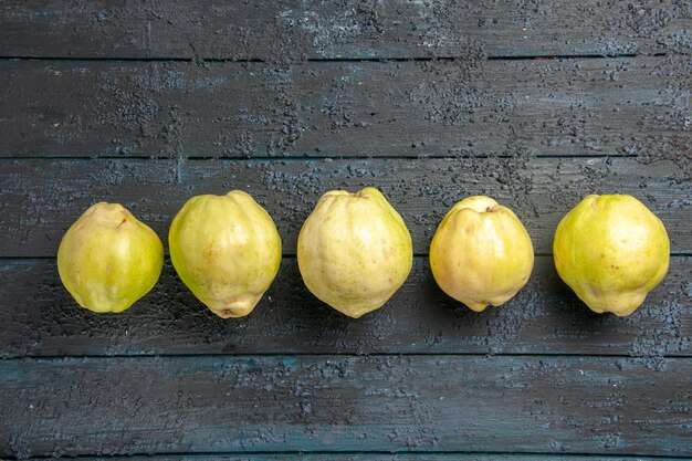 Vue de dessus coings mûrs frais fruits aigres bordés sur le bureau rustique bleu foncé plante fruitier mûr frais