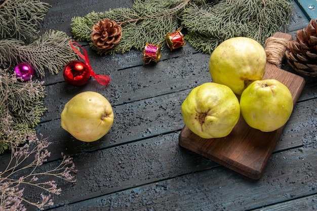 Photo gratuite vue de dessus coings mûrs frais fruits aigres sur un bureau rustique bleu foncé beaucoup de plantes fraîches arbre fruitier mûr