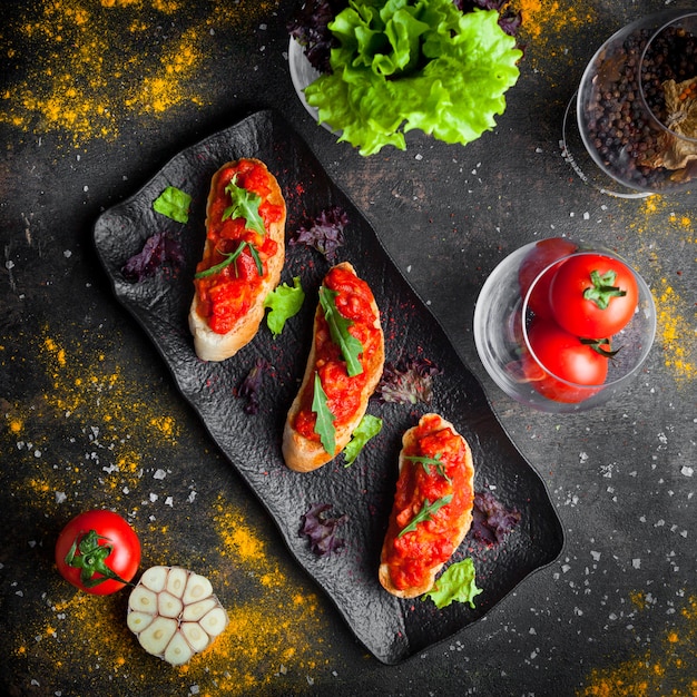 Vue de dessus collation avec et tranches de pain de dessus salade de tomates et roquette en plaque sombre