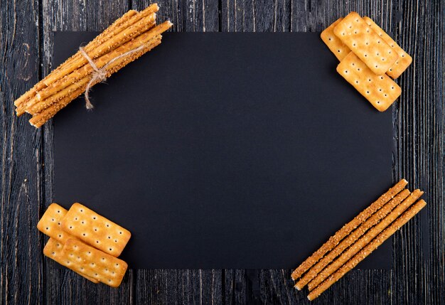 Vue de dessus des collations salées crackers et cracker sticks avec copie espace sur fond noir