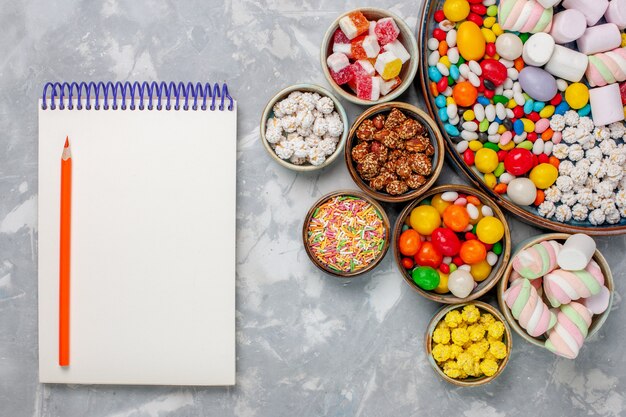 Vue de dessus de la composition de bonbons bonbons sucrés et délicieux avec de la guimauve sur le bureau blanc sucre goodie confitures sweet