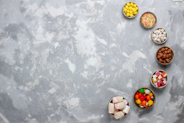Vue de dessus composition de bonbons différents bonbons colorés avec de la guimauve sur le bureau blanc sucre candy bonbon bonbon confitures thé