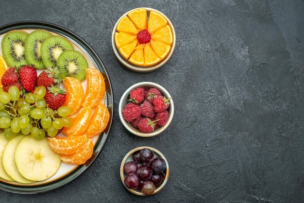 Photo gratuite vue de dessus composition de différents fruits fruits frais et tranchés sur fond sombre santé fruits mûrs frais et moelleux
