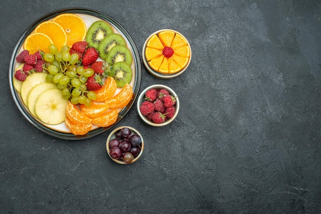 Vue de dessus composition de différents fruits fruits frais et tranchés sur fond sombre santé fruits mûrs frais et moelleux