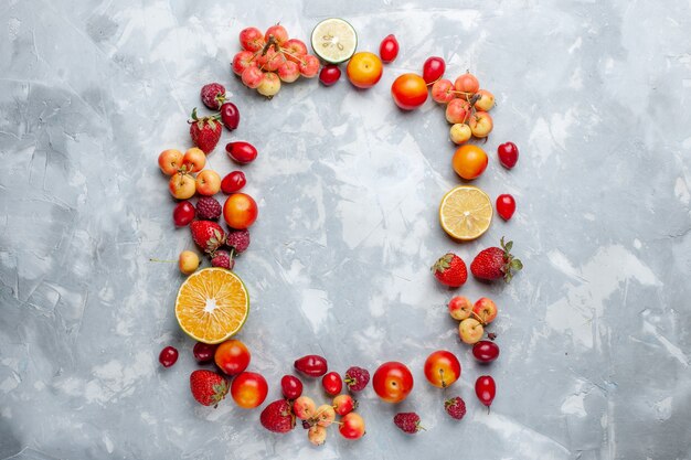 Vue de dessus de la composition des fruits citrons prunes et cerises bordées sur le bureau blanc fruits mûrs frais doux vitamine