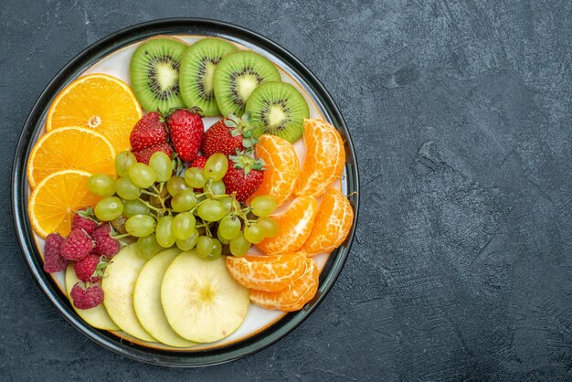 Vue de dessus composition de fruits délicieux fruits frais tranchés et moelleux sur fond sombre régime de santé mûr frais et moelleux