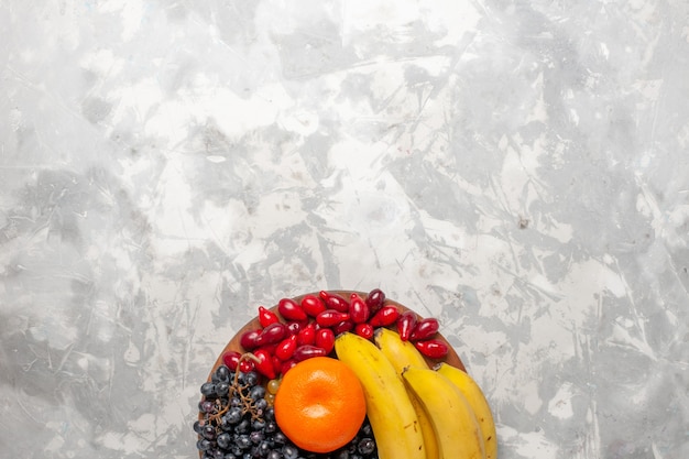 Photo gratuite vue de dessus composition de fruits frais bananes cornouiller et raisins sur blanc bureau fruits baies fraîcheur vitamine