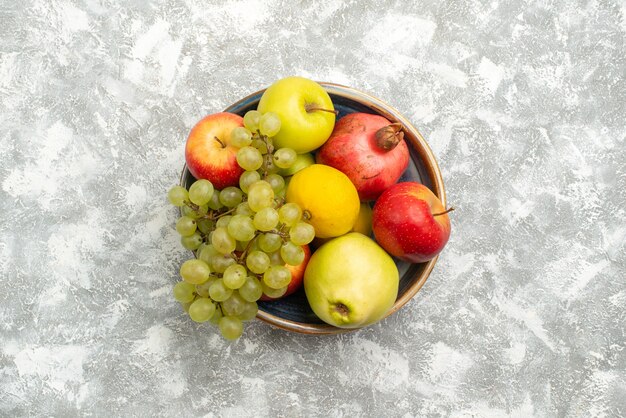 Vue de dessus composition de fruits frais pommes raisins et autres fruits sur le fond blanc fruits frais moelleux couleur mûre vitamine