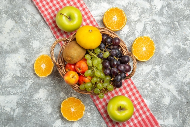 Photo gratuite vue de dessus composition de fruits frais raisins et prunes avec des tranches d'orange sur fond blanc vitamine fruits mûrs moelleux frais