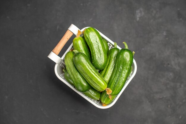 Vue de dessus des concombres verts frais à l'intérieur du panier sur fond sombre