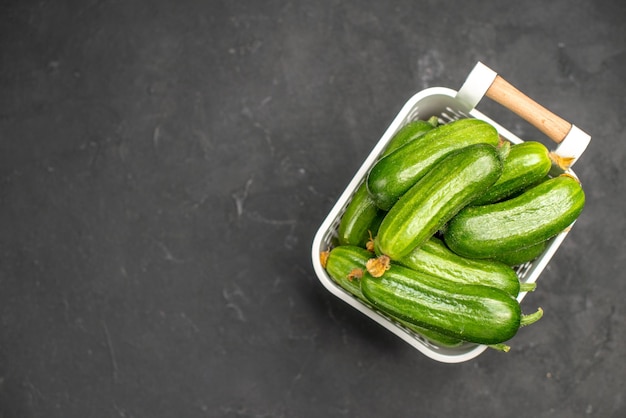 Vue de dessus des concombres verts frais à l'intérieur du panier sur fond sombre