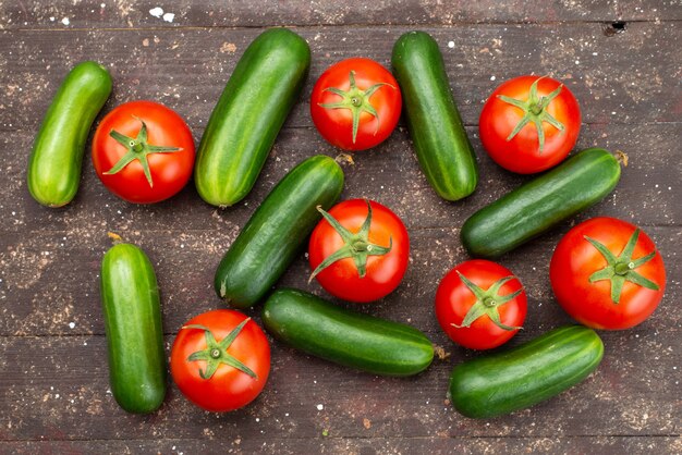 Vue de dessus concombres verts frais et mûrs avec des tomates rouges sur marron, nourriture pour arbres végétaux