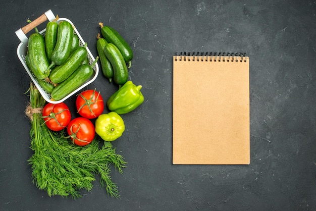 Vue de dessus des concombres verts frais avec des verts et des légumes sur fond sombre