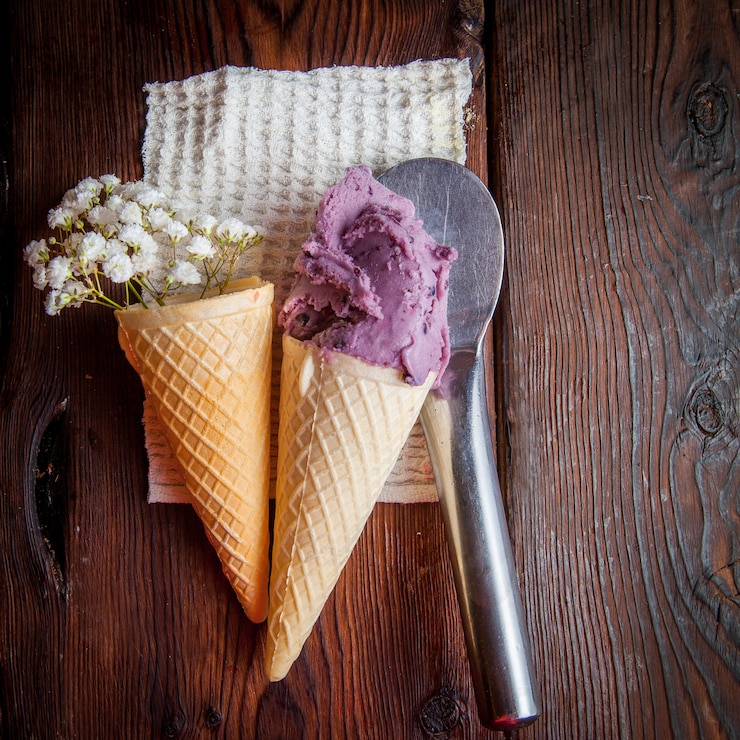 Photo gratuit vue de dessus cônes de gaufre avec crème glacée aux bleuets et gypsophile et cuillère à crème glacée dans des serviettes en chiffon