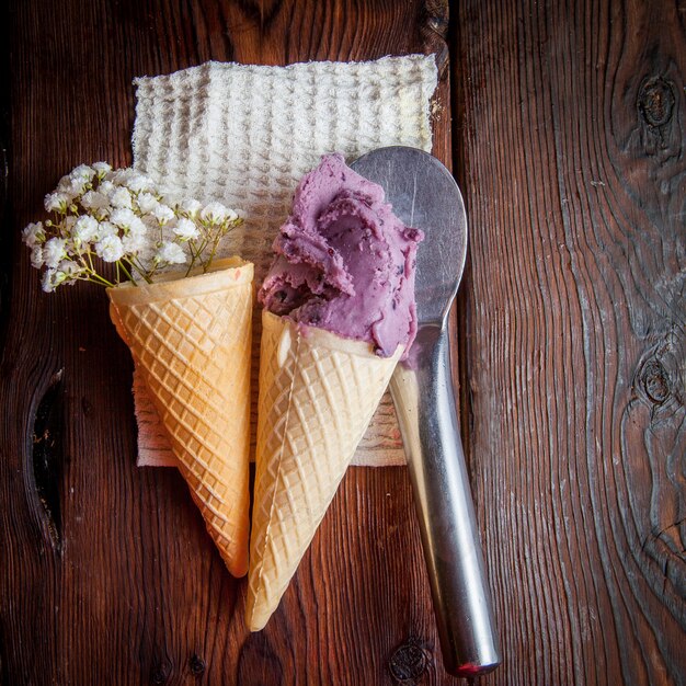 Vue de dessus cônes de gaufre avec crème glacée aux bleuets et gypsophile et cuillère à crème glacée dans des serviettes en chiffon