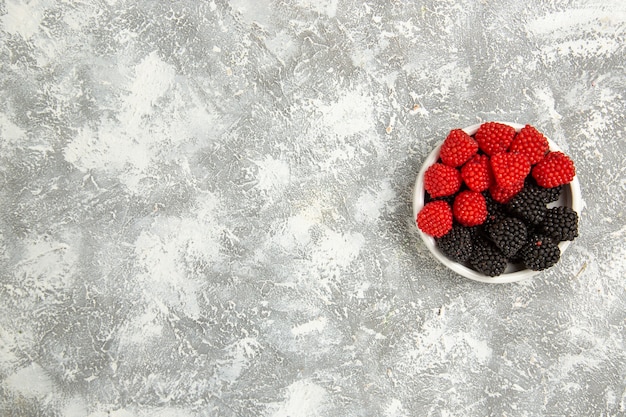 Vue de dessus confitures de baies fraîches bonbons sucrés à l'intérieur de la plaque sur la surface blanche berry candy sucre gâteau sucré tarte cookies