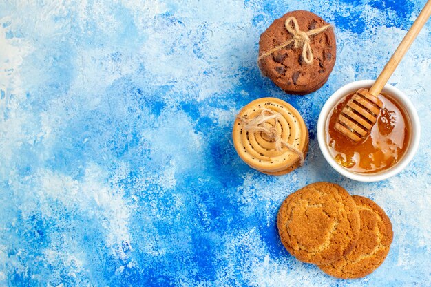 Vue de dessus des cookies attachés avec du miel de corde sur une table bleue