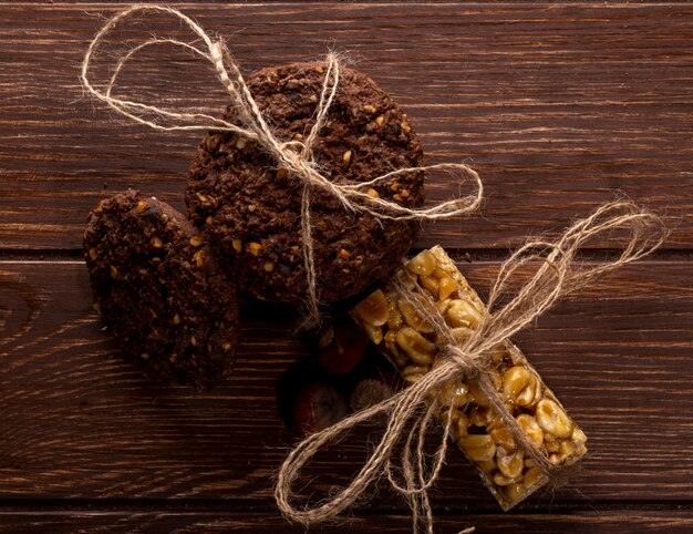 Vue de dessus des cookies aux pépites de chocolat avec des noix de céréales et du cacao attachés avec une corde sur bois