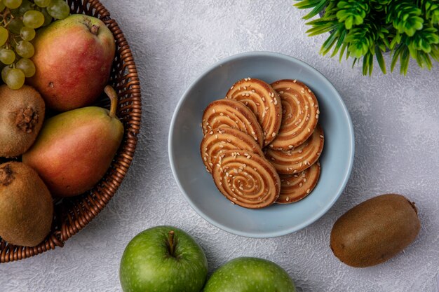 Vue de dessus des cookies dans un bol avec poire kiwi et pommes vertes sur fond blanc