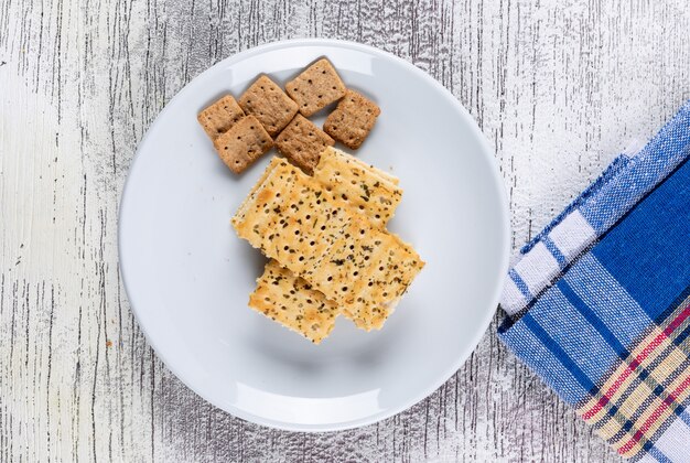 Vue de dessus les cookies sur la plaque et le tissu sur l'horizontale en bois blanc