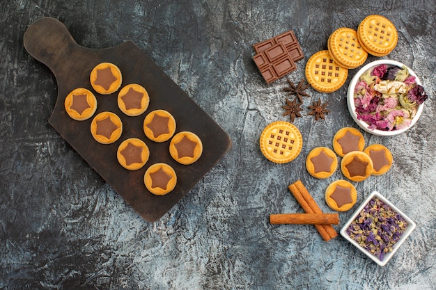 Vue de dessus des cookies sur plateau en bois et fleurs sèches sur fond gris